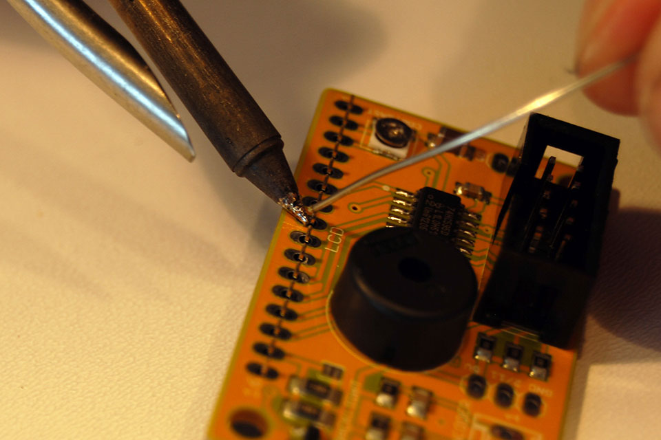 Next, solder the 16-pin female header for the LCD. It is inserted from the BOTTOM, the side that says 'LCD goes on this side'. Solder only the middle pin first.